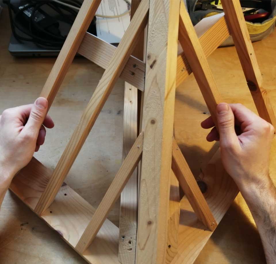 Deux mains qui assemble une structure en bois